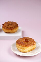 Grainy Donat or Donut or Doughnut with caramel and Lotus biscuit crumbs. Selective focus, pink pastel background