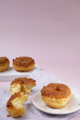 Obraz na płótnie Canvas Grainy Donat or Donut or Doughnut with caramel and Lotus biscuit crumbs. Selective focus, pink pastel background
