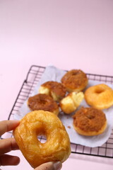 Grainy Donat or Donut or Doughnut with caramel and Lotus biscuit crumbs. Selective focus, pink pastel background