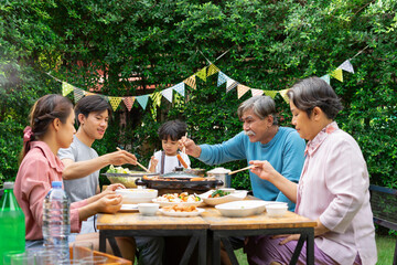 Family enjoy eating BBQ dining at yard to celebrate speacial occasion.