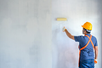 Young Asian painters have The joy of painting interior white walls with paint roller in new house.