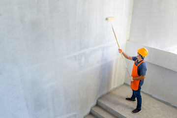 Young Asian painters have The joy of painting interior white walls with paint roller in new house.