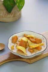 A plate of Kolak Ubi Nangka or Indonesian dessert made from Sweet Potato and Jack fruit as a compote. Based on coconut milk, palm sugar and Pandanus leaves in isolated gray background