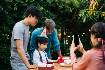 Asian family celebrate kid birthday party together outdoor at yard.