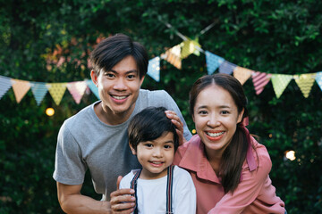 Asian family son, father, and mother in birthday party outdoors.