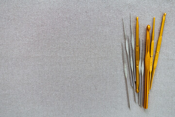 Crochet needles, crochet hook, Shepherds' hooks, in silver and gold color, on a grey background copy space.
