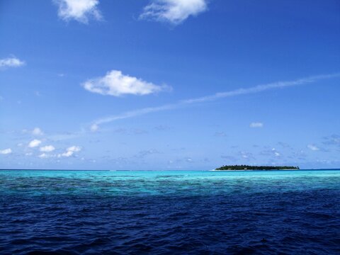 Ocean, island and sky on a sunny day, scenic view with 
 many shades of blue.