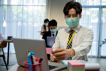 Obraz premium Asian employees work wear protective face mask due covid working in modern office,Working and social distancing concept.