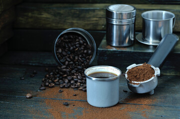 coffee bean cup and porta filter with coffee powder inside and Vietnam Drip Coffee on wooden table