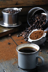 coffee bean cup and porta filter with coffee powder inside and Vietnam Drip Coffee on wooden table