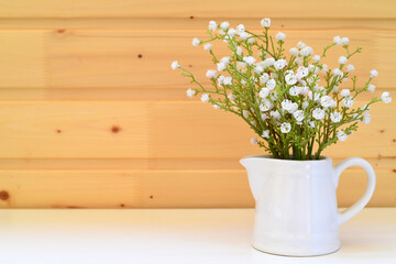 Bouquet of gypsophila in a glass pot against a wooden wall. Spring background with copy space