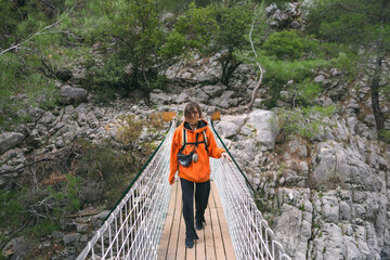 A girl with a backpack walks on a suspension bridge