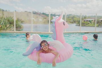 Girl in unicorn inflatable ring, Kids having fun playing in pool with father at home, staycation concept