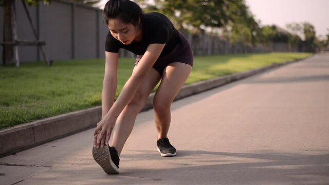 Young woman runner stretching before running outdoors. happy asian woman warming up before outdoor workout.