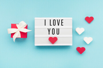 Valentine's Day holiday card. Red gift box, hearts on pastel blue background. Valentines day concept.