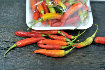 Some red chilies on a black wooden base and a bunch of red chilies in a plastic box