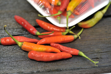 Some red chilies on a black wooden base and a bunch of red chilies in a plastic box