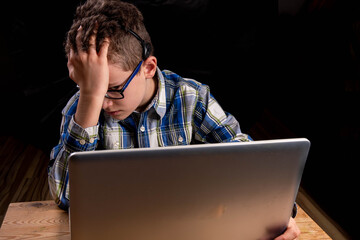 Boy with glasses and shirt on laptop learning burn out