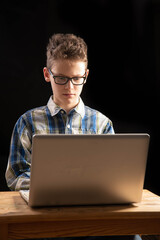 Boy with glasses looks strained into laptop