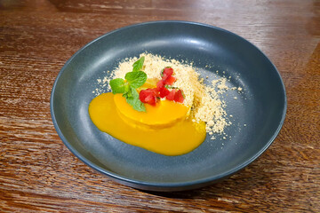 Mango cheesecake on gray plate.