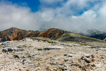 Rocky alpine landscape with clouds rising from the gorge
