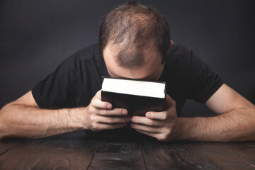 Caucasian man praying in the dark room.