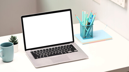 Fototapeta premium Mock up laptop computer with blank screen, notebook, stationery and coffee cup on creative designer workspace.