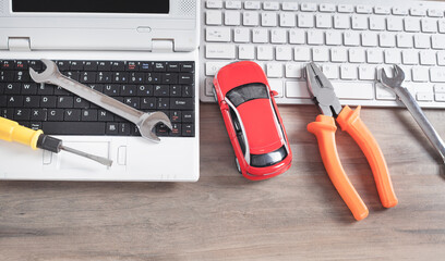 Toy car, wrench, screwdriver, pliers and computer keyboard.