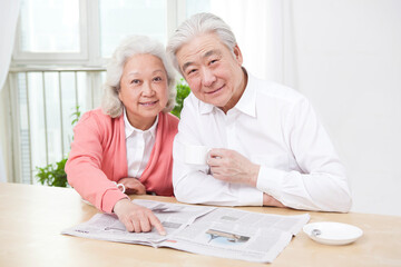 The happy old couple are reading the newspaper