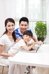 A happy family of three using laptop 