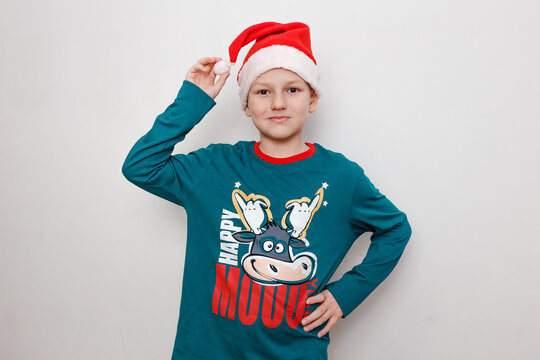 A nine-year-old boy in green pajamas with picture of a bull and a red cap on a white background. Happy year of the bull.