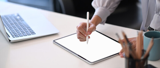 Cropped shot of businesswoman hand holding stylus pen writing on screen of digital tablet at office...