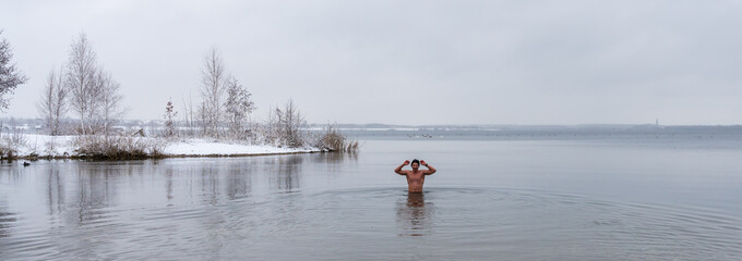 A man goes into a lake in winter for ice swimming