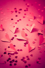 Red paper hearts on red background as background.