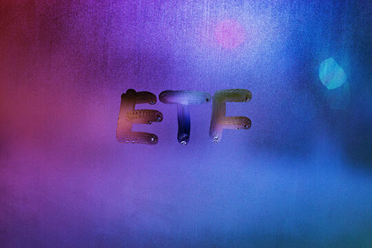 abbreviation word etf - exchange traded funds - handwritten on foggy glass window at night with neon blue back street light
