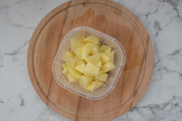 Peeled fresh potatoes are on the table on a wooden board potatoes cut into pieces