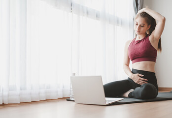 Woman learned online workout stretching excercise fitness class at home from laptop. Self isolation and workout at home during COVID-19