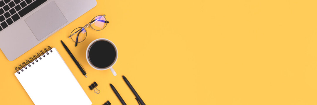 Banner with organized workspace with coffee, laptop and stationery on a yellow background. Online education, remote job concept with copyspace.