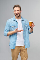 Portrait of young handsome caucasian man in jeans shirt over light background holding cup of coffee to go