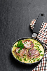 Tenderloin medallions with mustard sauce in frying pan on black stone background