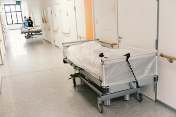 A white covered empty bed on a hospital floor.