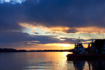 Fragment of the ship near the pier against of a colorful sunset over Danube river