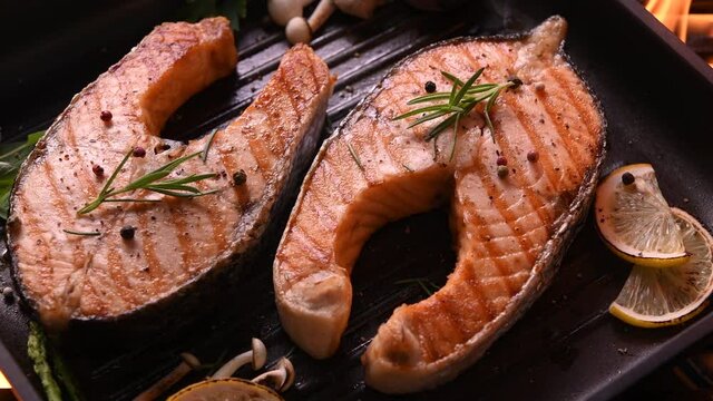 Grilled salmon fish with various vegetables on pan on the flaming grill