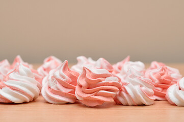 Pink and white meringues on a wooden table