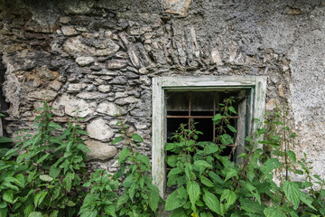 house made of stones with a window and large nettles