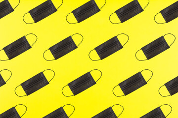 Black medical mask pattern on yellow background. Epidemic coronavirus COVID-19 concept.