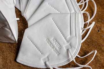 Face surgical white mask FFP2 KN95 N95 disposable for adults on travertine background. Masks are...