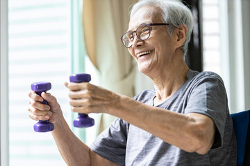 Strong asian senior woman working out,lifting dumbbell weights for strength training,old elderly...