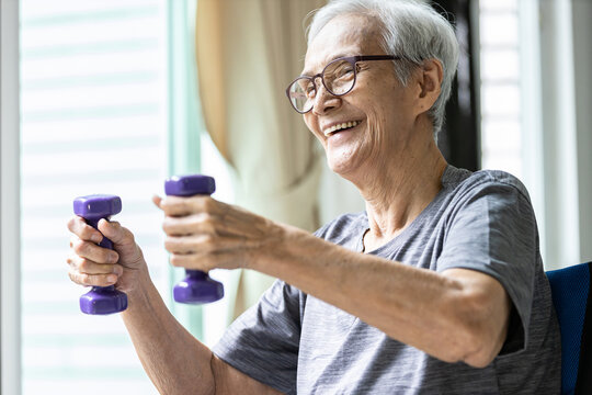 Strong asian senior woman working out,lifting dumbbell weights for strength training,old elderly using dumbbells while exercising,physical therapy in nursing home,health care,healthy lifestyle concept