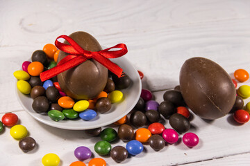 Easter composition with chocolate eggs on white wooden background